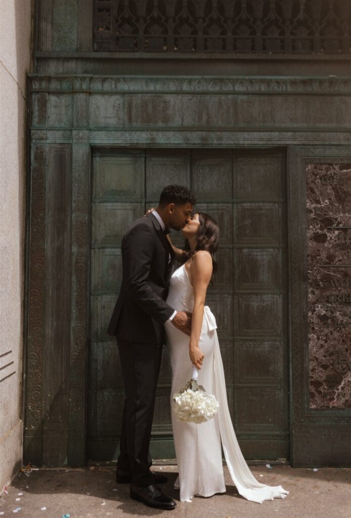 portrait of the newlyweds kissing outside of the NYC city hall